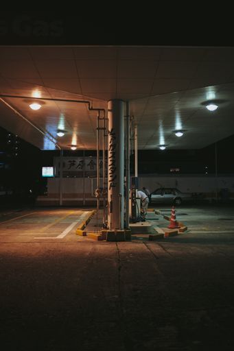 A vertical shot of a petrol station with a car parked nearby during nighttime