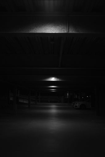 A vertical black and white shot of an underground parking lot