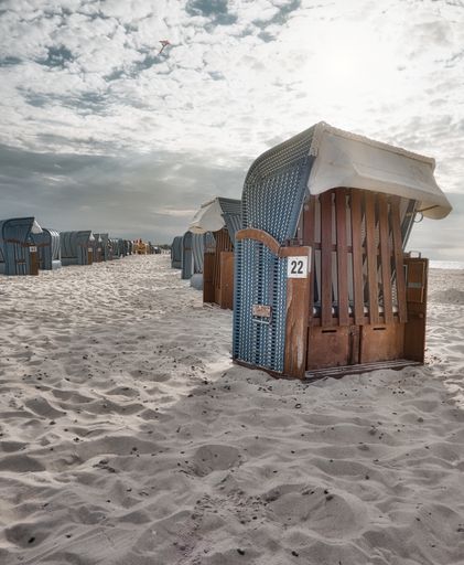 A beautiful view of aligned wooden rooms on deserted sandy beach with a gray sunny sky