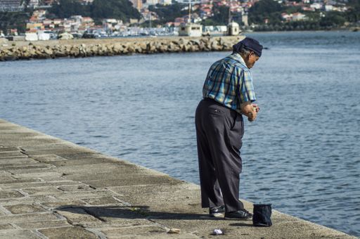 old man fishing for crabs with cages in the port