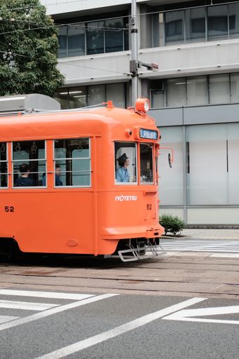 A vertical shot of an orange train on a street running
