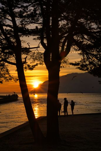 A silhouette of people standing by the beautiful Lake Biel during the sunset