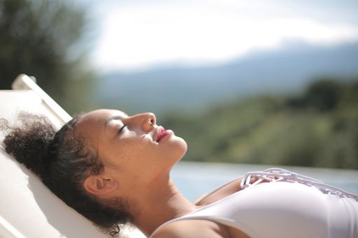 A closeup of an African woman peacefully relaxing by the pool under the sun