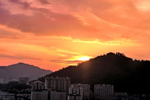 A silhouette shot of buildings against hills during a breathtaking sunset