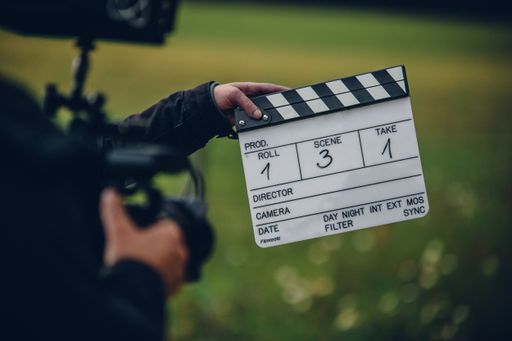 A shallow focus shot of the cameraman holding a clapperboard in the field