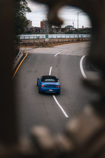 vertical shot of Blue car driving fast in front of the Boston skyline