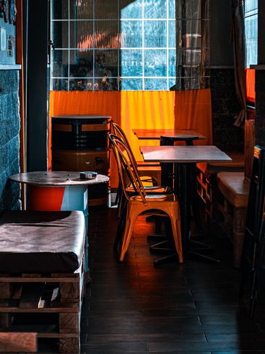 A vertical shot of a cafe corner with little tables, few chairs and colorful walls