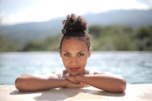 A closeup shot of a smiling black-haired woman in the pool
