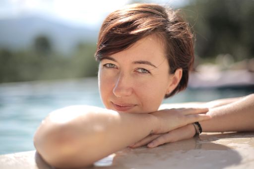 A closeup shot of a smiling black-haired woman in the pool