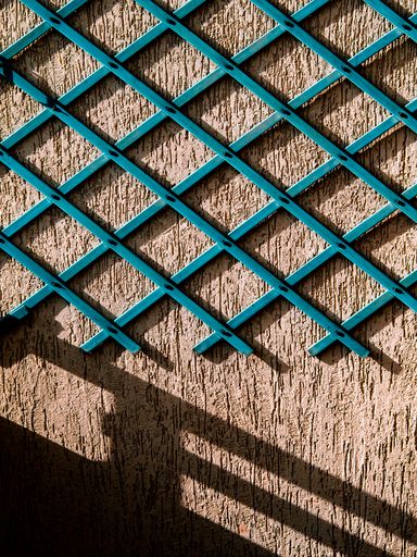 A vertical shot of rough wall and blue wooden lines on it shaping rhombuses
