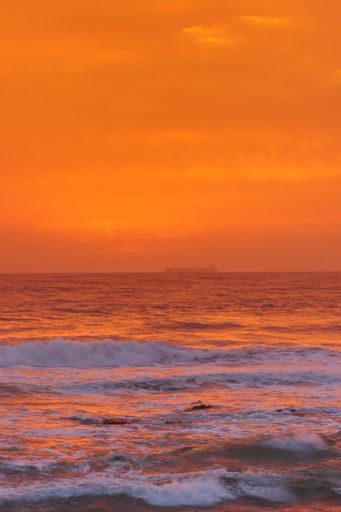 A vertical shot of a sunset above the sea