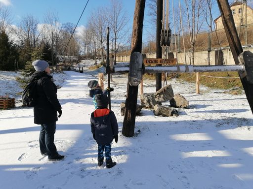 A shot of a woman with two children standing next to an old crane at the Middle Age Technology park.