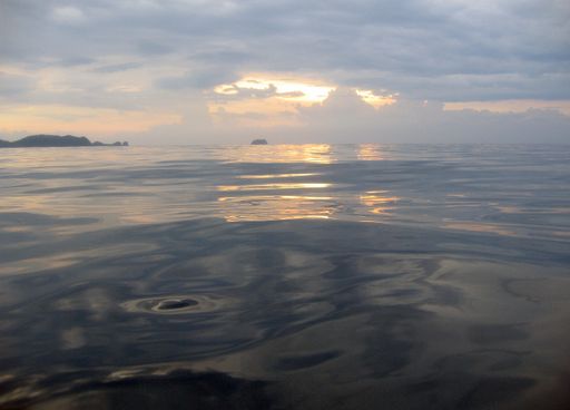A wide shot of a sea under a cloudy sky during sunset