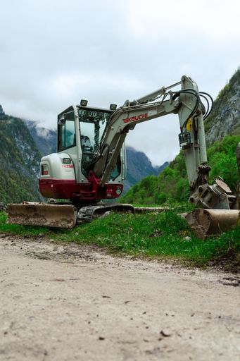 A vertical shot of a small excavator standing next to a footpath