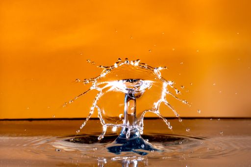 A closeup shot of a water splash in a studio on an orange background