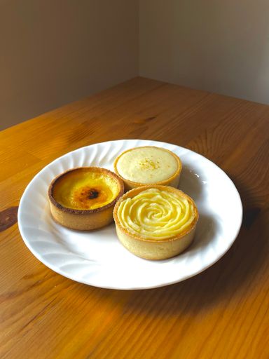 A vertical shot of various creamy tarts on the white plate on the wooden table