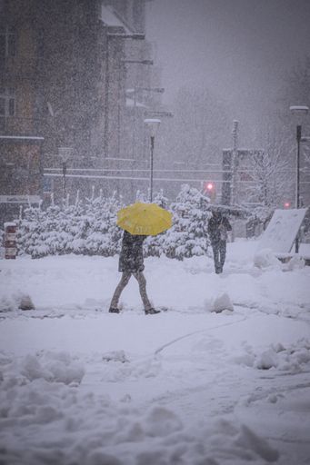A vertical shot of people walking on a street during snowstorm