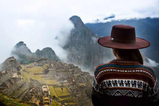 A back view of a girl looking at the scenery of the mountain Machu Picchu and the Incas ruins