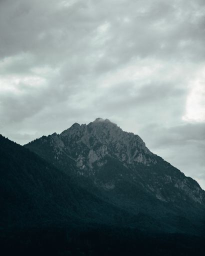 A vertical of mountains covered with pine forests on a gloomy day in Konigssee, Bavaria, Germany