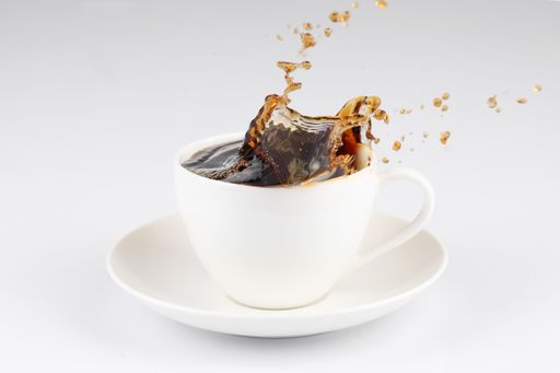 A coffee splashing out of a cup isolated on white background.