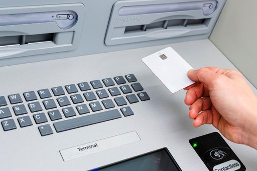 A man using a credit card at a contactless ATM