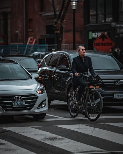 A lady riding a bike surrounded by cars in downtown Toronto, Canada