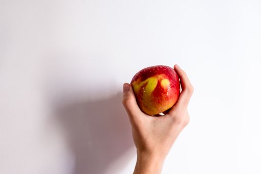 A hand holding a red apple in the white background