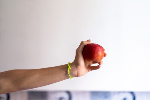 A hand holding a red apple in the white background
