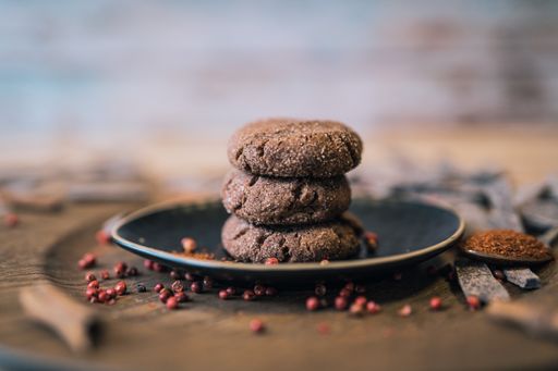 A shallow focus shot of chocolate cookies on a black plate on a wooden table