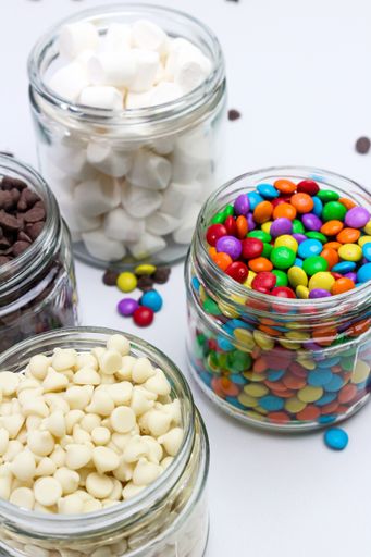 A vertical closeup of the glass jars with different sweets.