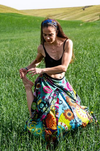 The young woman doing yoga movements in the grass field