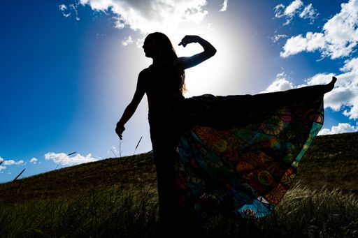The silhouette of a young girl doing yoga exercises in the field
