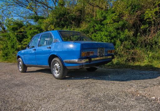 A view of a blue Alfa Romeo Alfetta in a field