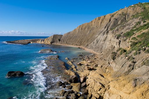 Steep blue clay slopes, with flaking debris forming scree on limestone along the coast of Xatt l-Ahmar, Ghajnsielem, Gozo, Malta, on a sunny day.