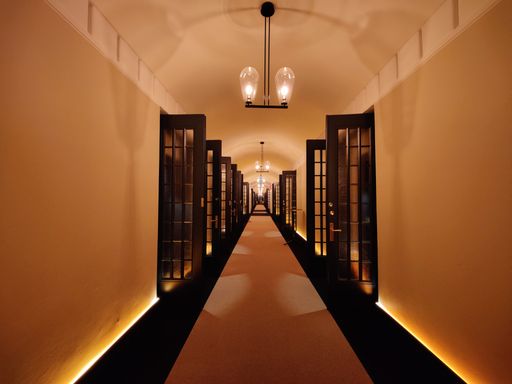 A long corridor with open doors and lights
