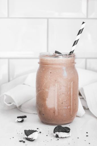 A vertical shot of a chocolate smoothie with oreos in a glass jar