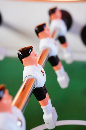 A vertical shot of a plastic figure of a table soccer in white and black uniform