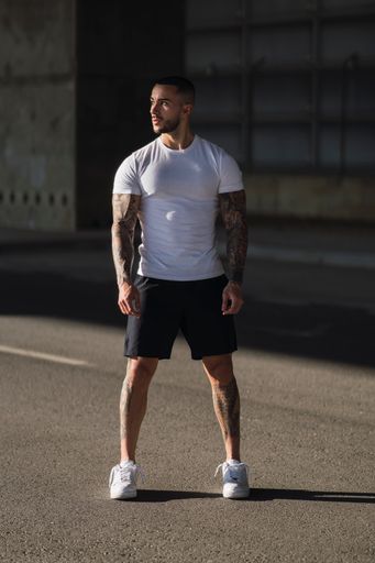 An athletic young man in a white t-shirt standing on the street
