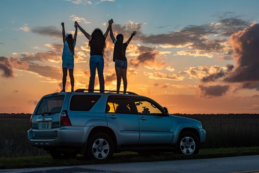 Three ladies on a Toyota Land Cruiser at sunset in Everglades, Florida, the USA