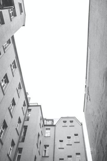 A vertical low angle greyscale shot of the tall buildings captured during the day