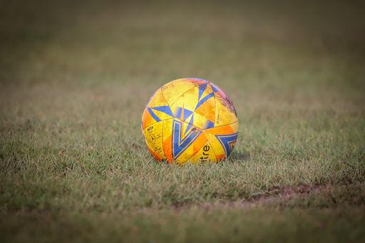 A closeup of the yellow football ball on the green lawn.