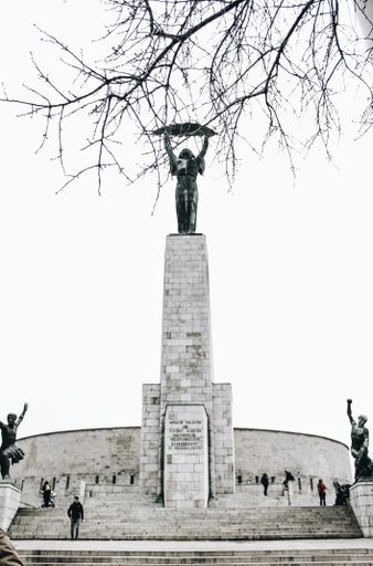 A vertical shot of a statue on top of the stairs with a clear sky in the background