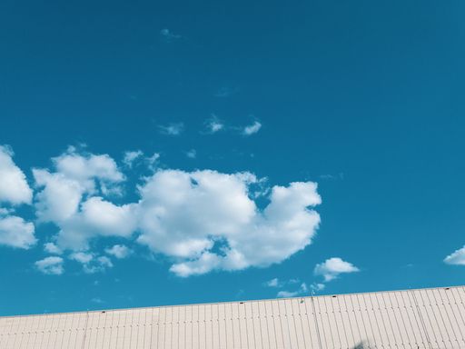 The roof of a house and a beautiful white cloud with the light blue sky in the background
