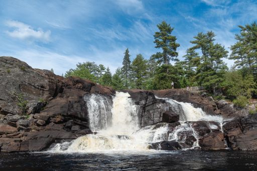 A view of one man standing at the edge of Muskoka High Falls on a sunny day, Bracebridge, Ontario, Canada