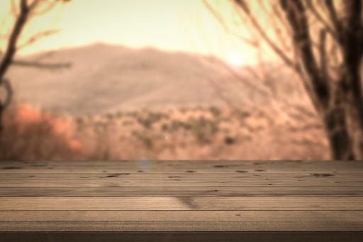 A wooden table against the blurry background with mountains gleaming under the sunrays