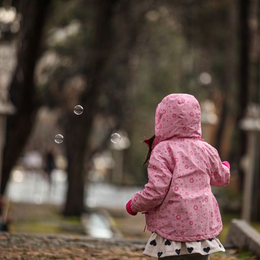 A baby girl playing bubble in the park