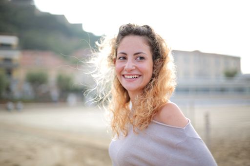 A smiling blonde woman surrounded by buildings