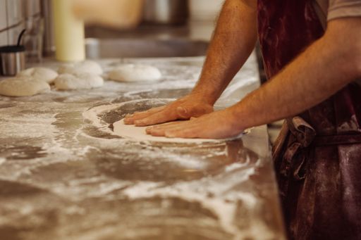 A cook making pizza dough in a kitchen