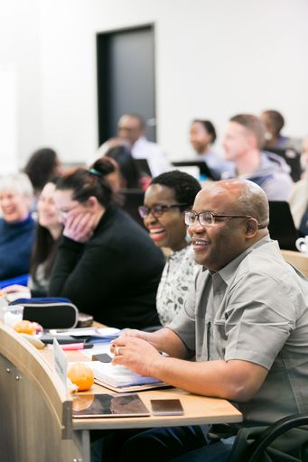 A vertical shot of diverse adult delegates attending a business lecture in the classroom