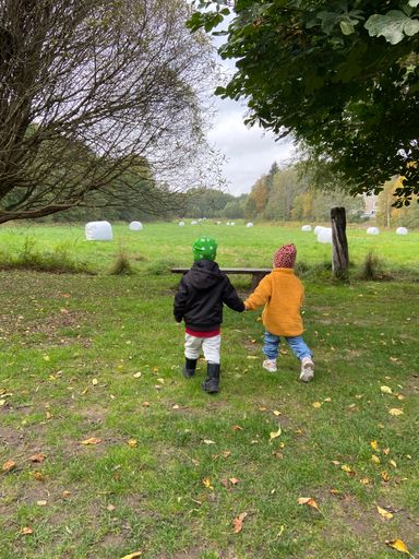 A view of cute children playing in a green field on a cloudy day